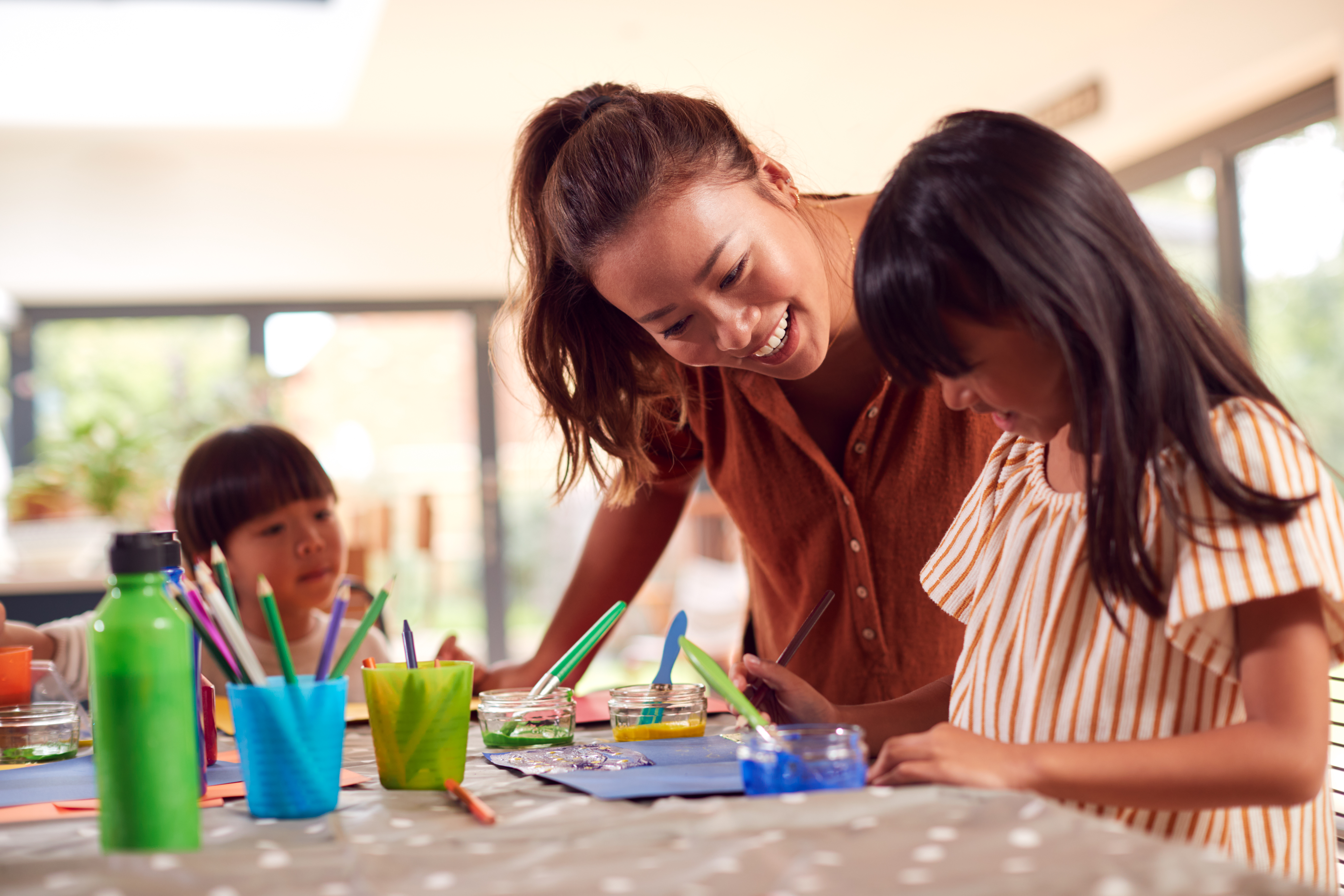 Asian Mother With Children Having Fun With Children Doing Craft On Table At Home
